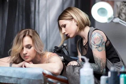 Woman getting tattooed by female artist